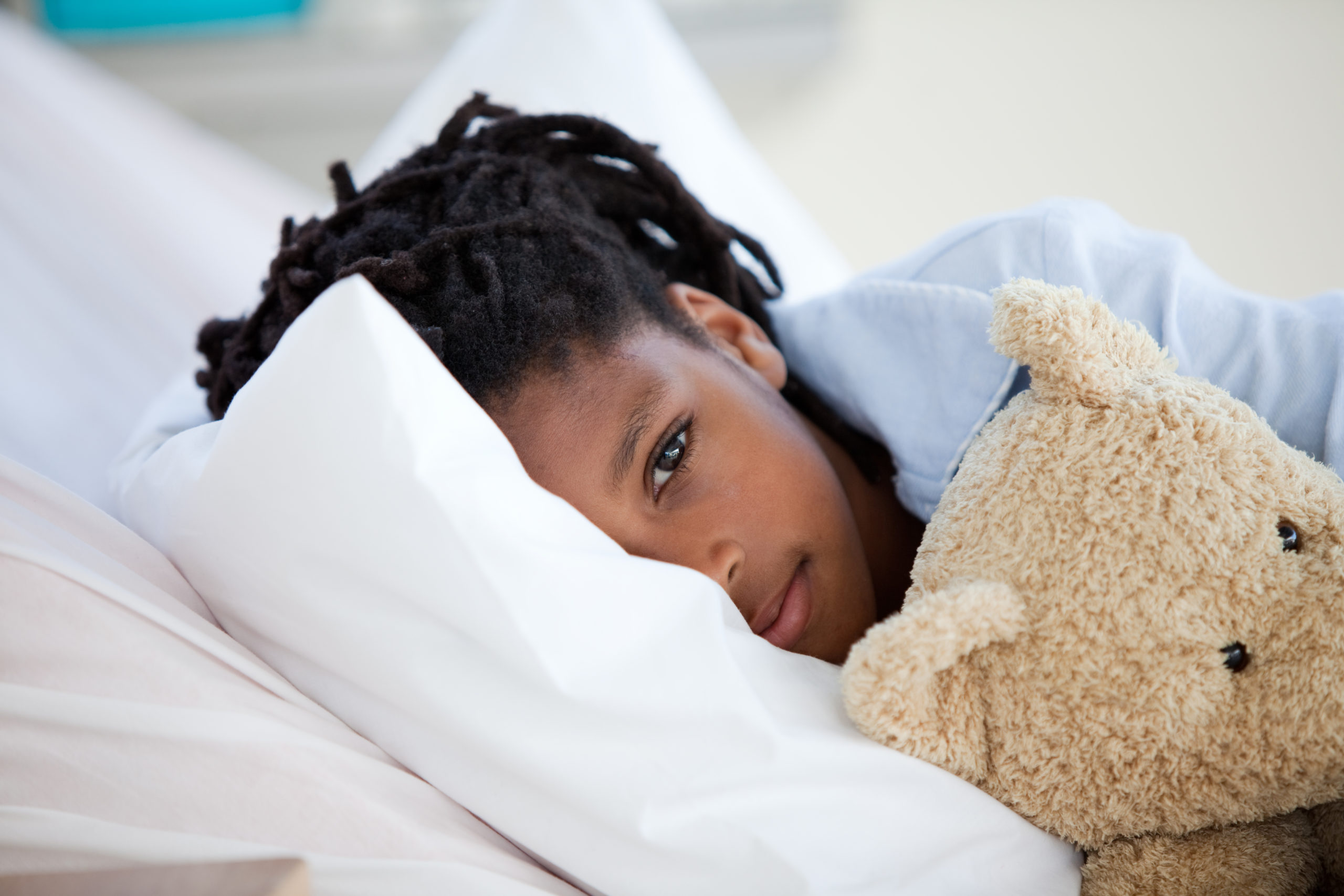 Young african american Boy in Hospital Black boy hugging a teddy bear in a hospital bed