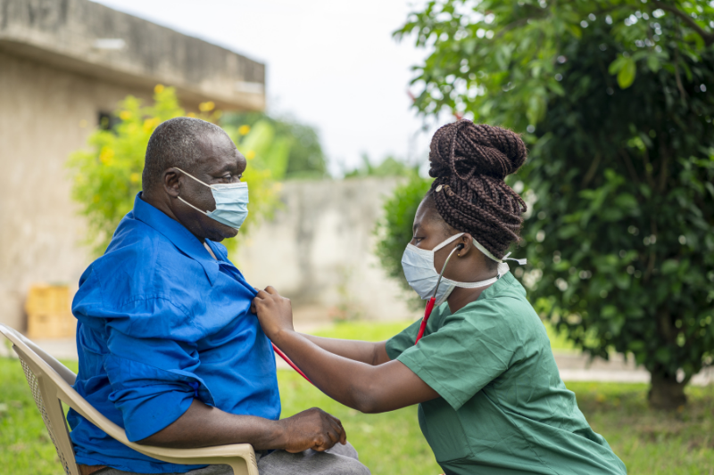 Black nurses listening to the heartbeat of an older Black man