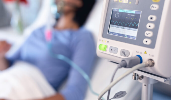 Ventilator monitor and african american female patient in hospital bed